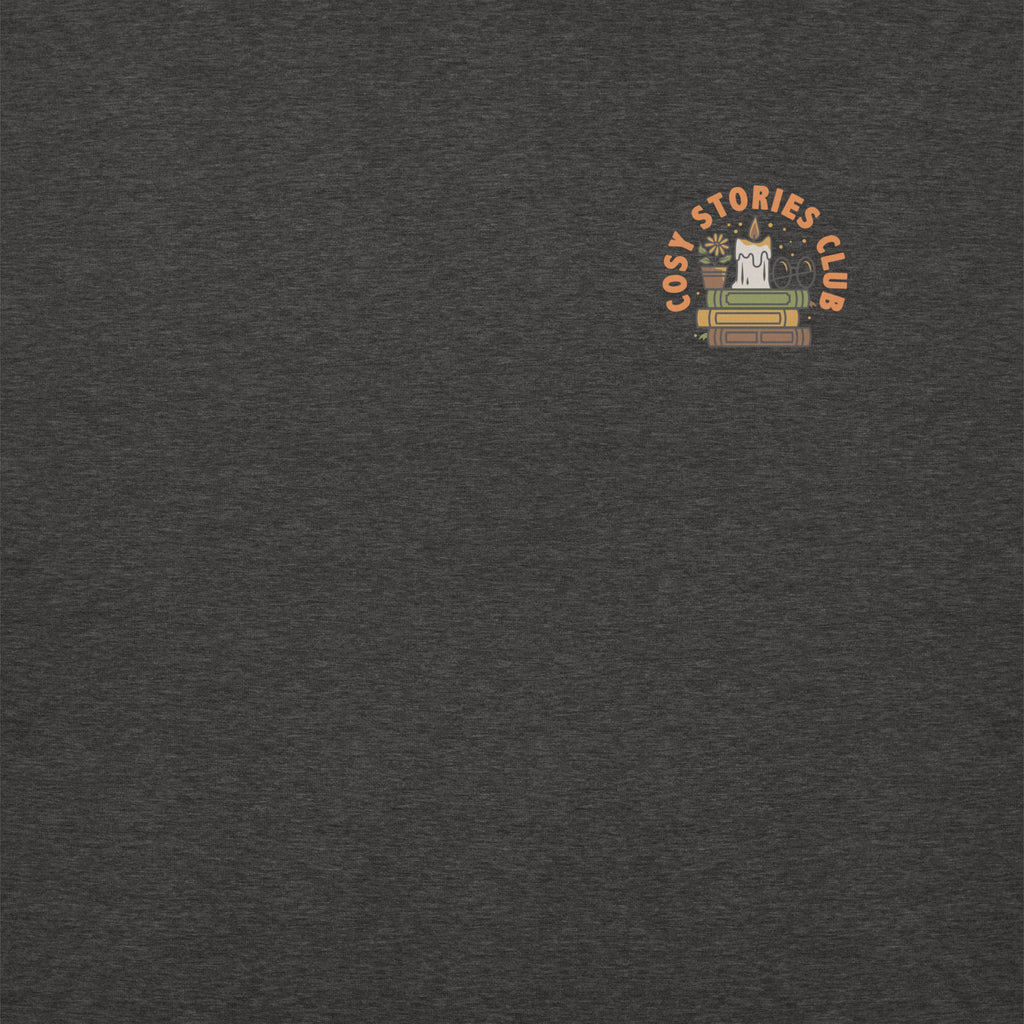 grey sweatshirt featuring a design that reads cosy stories club in orange. in center of text is a candle on top of 3 books stacked.