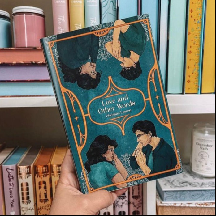 Book titled 'Love and Other Words' held in front of a bookshelf with other books.