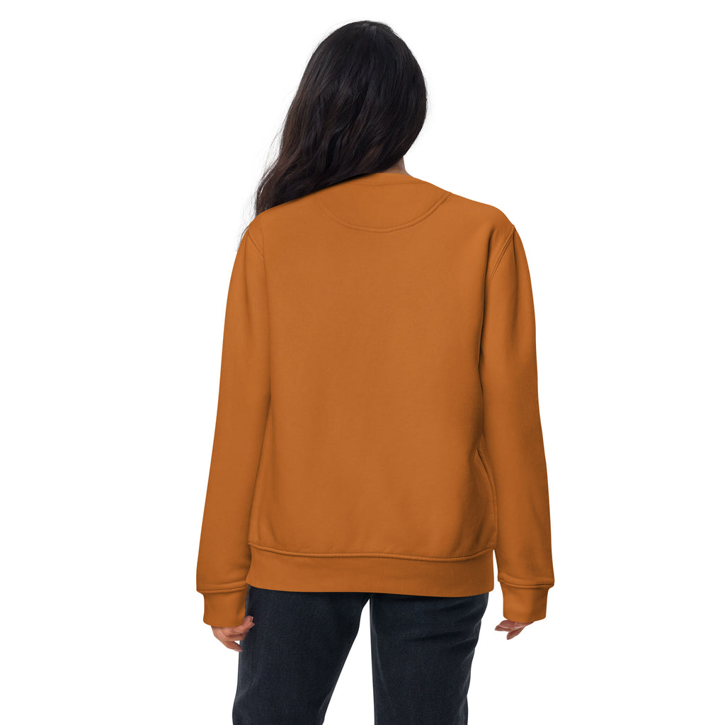 Woman standing with back facing towards camera. Wearing an orange sweater. On a white background
