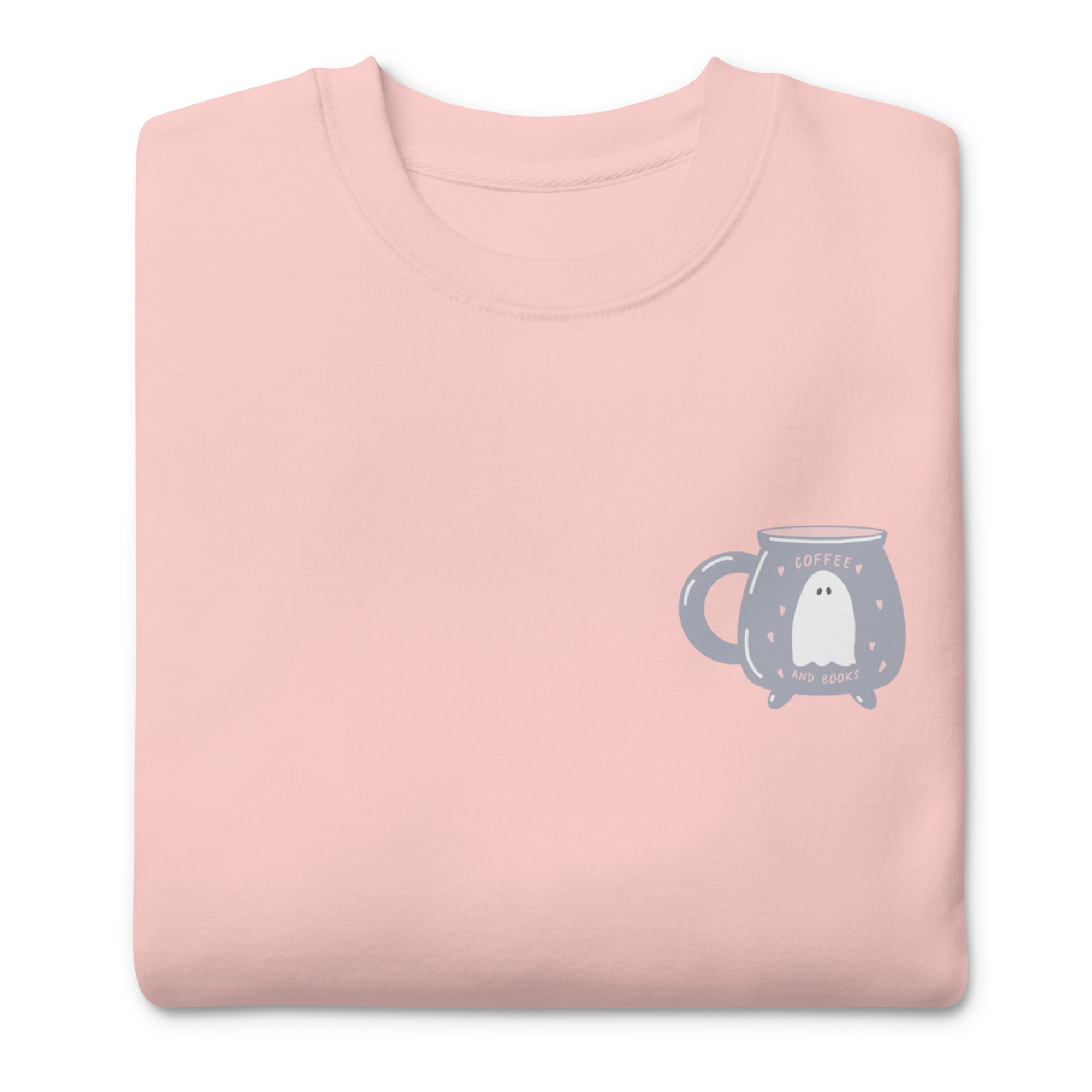 Pink sweatshirt with a ghost design on a mug, text reads "coffee and books" folded on a white background