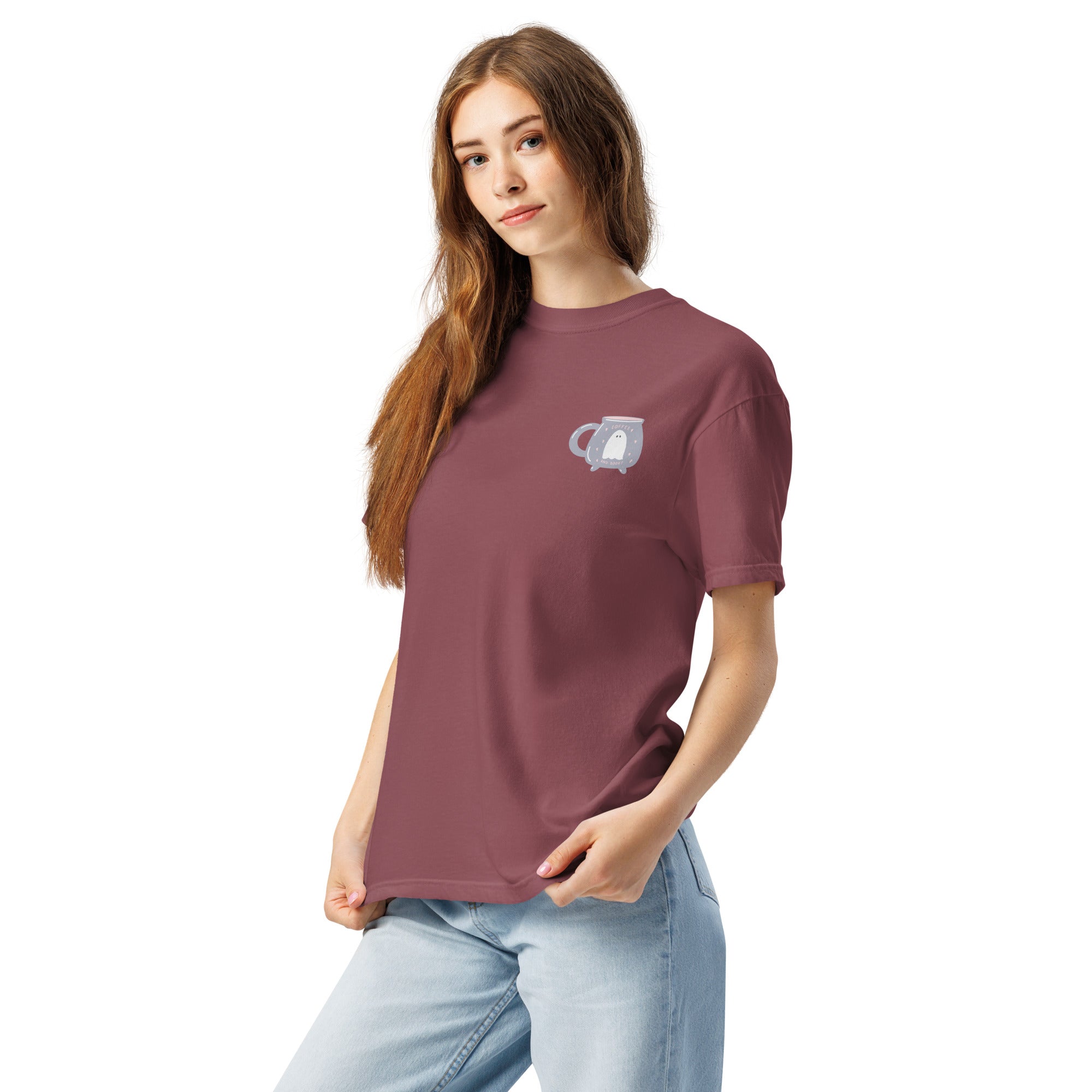 Woman wearing a maroon t-shirt with a design that features a ghost inside of a cauldron shaped mug on a white background