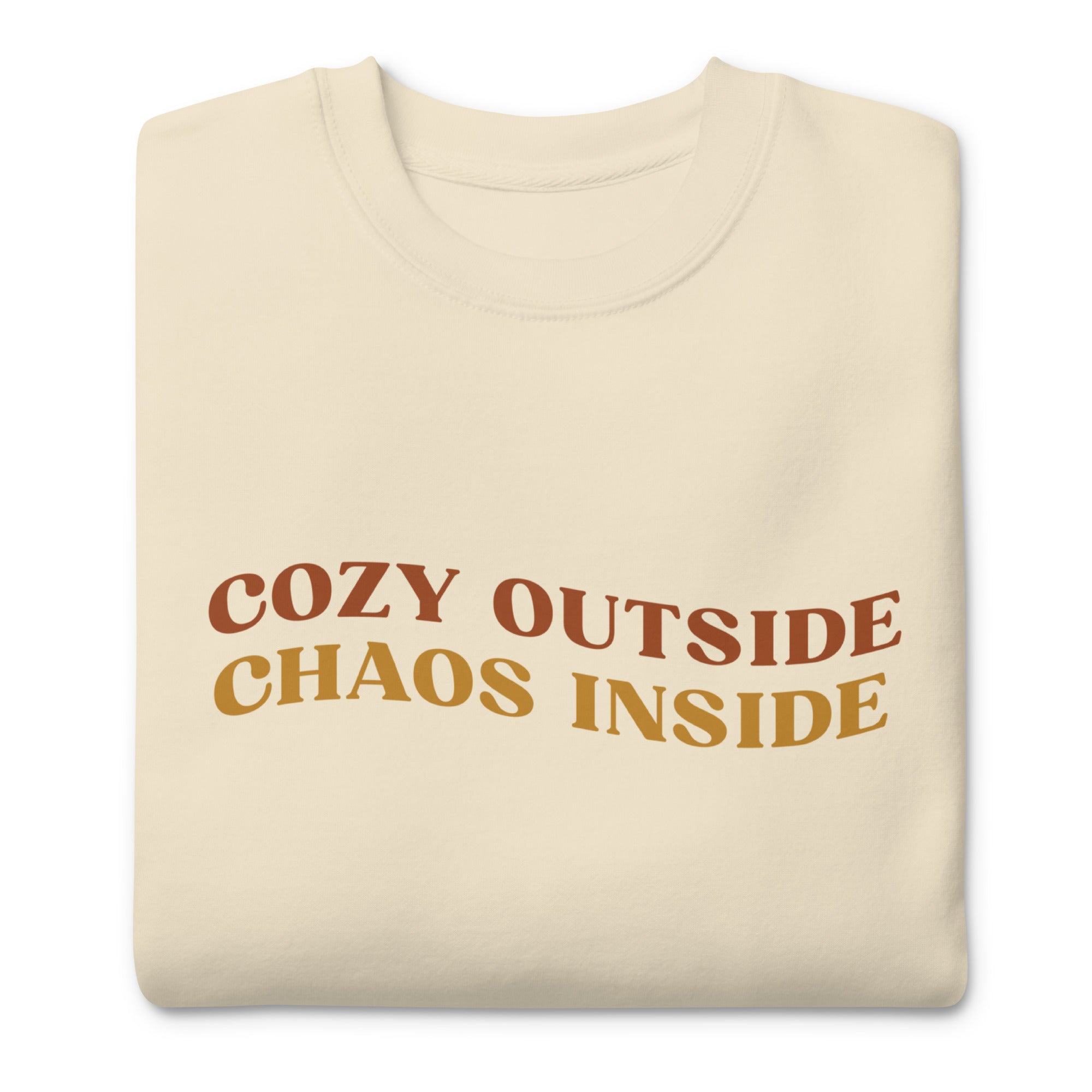 cream sweater with the words "cozy outside chaos inside" written in the center. displayed on white background.